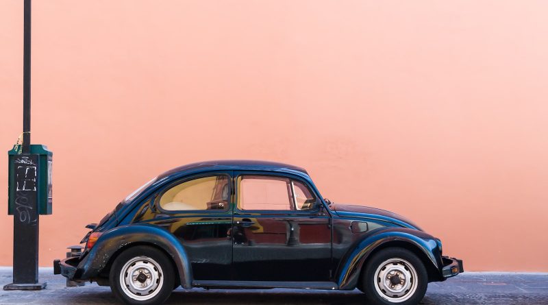 black Volkswagen Beetle beside beige wall